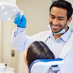 Dentist pulling light close to examine woman’s teeth