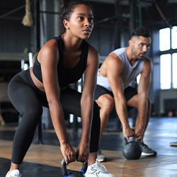Woman and man lifting weights in workout class
