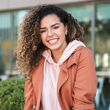 Woman in jacket and hoodie smiling outside