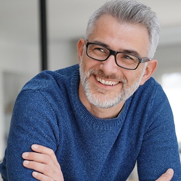 Man with a blue shirt and glasses leaning forward and smiling