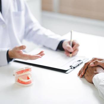 Patient and dentist discussing treatment plan while sitting at desk