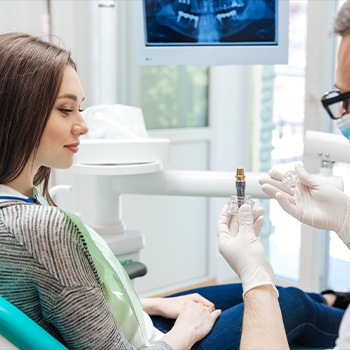 A dentist showing a patient a dental implant model