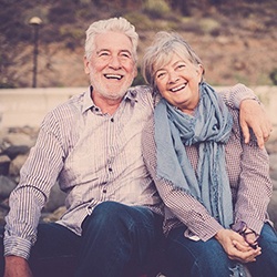 An older couple smiling while sitting outside