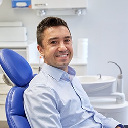 Man in blue collared shirt smiling in dental chair