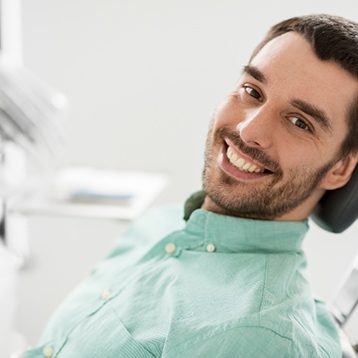 Male patient in green shirt smiling in treatment chair