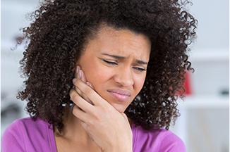 Grimacing woman holding jaw