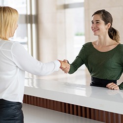 Patient and receptionist shaking discuss making veneers affordable in Wylie 