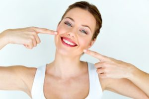 woman smiling and pointing at her teeth