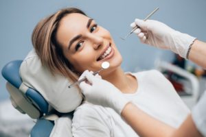 Woman smiling in dental chair after choosing dental implants