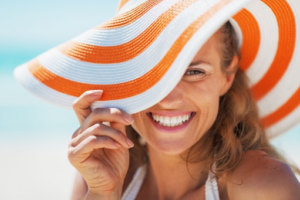 Woman in sunhat smiling brightly at the beach