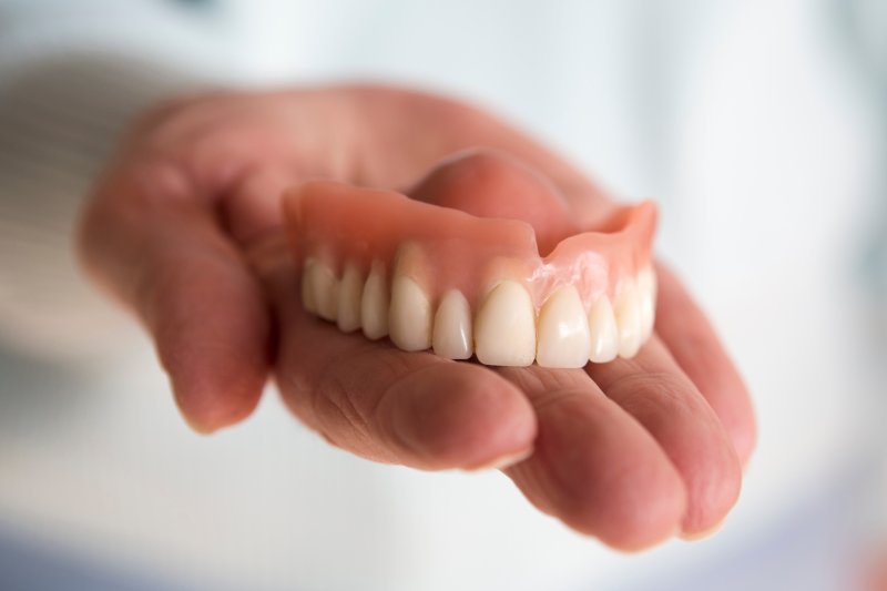A blurred woman holding a denture in her hand